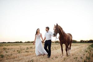 la mariée en robe blanche et le marié en chemise blanche en promenade photo