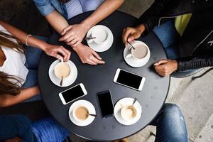 mains avec des tasses à café et des smartphones dans un café urbain. photo