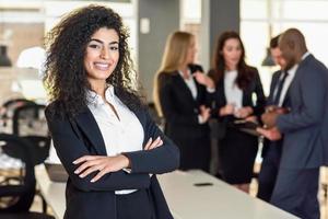 chef de femme d'affaires dans un bureau moderne avec des hommes d'affaires travaillant en arrière-plan photo