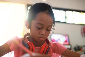 une jolie fille asiatique fait ses devoirs dans sa maison pendant la journée photo