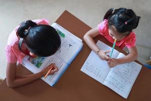 une jolie fille asiatique fait ses devoirs dans sa maison pendant la journée photo