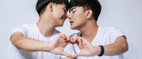 deux jeunes hommes aimants se regardent et font une main de symbole d'amour. photo