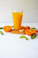 jus d'orange et fruits oranges frais sur un fond en bois blanc