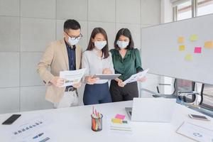 les employés de l'entreprise portant un masque pendant le travail au bureau pour maintenir l'hygiène suivent la politique de l'entreprise. préventif pendant la période d'épidémie de coronavirus ou de covid19. photo