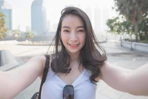 belle femme touristique solo asiatique prenant des selfies sur un appareil photo dans le centre-ville de la ville urbaine. voyage de vacances en été.