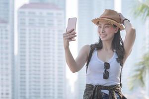 belle femme de tourisme asiatique prenant des selfies sur un smartphone dans le centre-ville urbain. voyage de vacances en été.