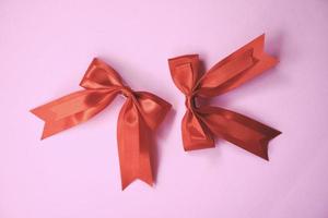 noeud de ruban rouge sur fond rose deux arc cadeau en épingle à cheveux vacances parfaites fait à la main photo