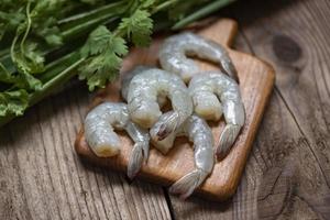 crevettes crues sur fond de planche à découper en bois pour la cuisson - gros plan de crevettes fraîches ou de crevettes, fruits de mer de plateau photo