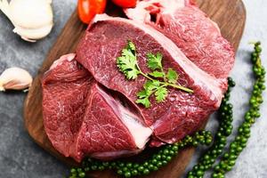 viande de boeuf crue sur une planche à découper en bois sur la table de la cuisine pour la cuisson du steak de boeuf rôti ou grillé avec des ingrédients herbes et épices protéines animales de boeuf frais photo