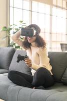 femme latine à l'aide d'un casque de réalité virtuelle sur canapé photo