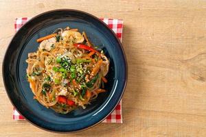 nouilles japchae ou vermicelles coréennes sautées aux légumes et au porc garnies de sésame blanc photo