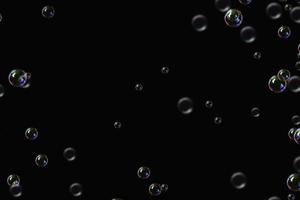 bulles transparentes motif de savon superposition de particules abstraites éclaboussures d'eau sur fond noir. photo