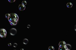 bulles colorées transparentes motif de savon superposition de particules abstraites éclaboussures d'eau sur fond noir. photo