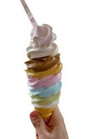 motif de dessert glacé à saveur arc-en-ciel de crème glacée dans une main de cône de gaufre marron tenant sur blanc. photo