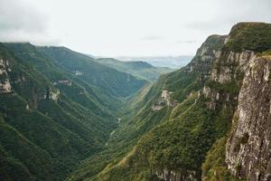 canyon de fortaleza avec des falaises rocheuses abruptes couvertes d'une épaisse forêt et de brouillard remontant le ravin près de cambara do sul. une petite ville de campagne dans le sud du brésil avec des attractions touristiques naturelles étonnantes. photo