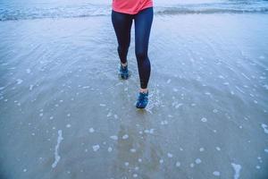 femme jogging séance d'entraînement sur la plage le matin. détendez-vous avec la promenade en mer. en été photo