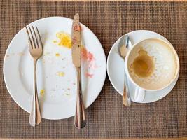 plats blancs vides et tasse de café avec après le petit déjeuner sur une table en bois. photo