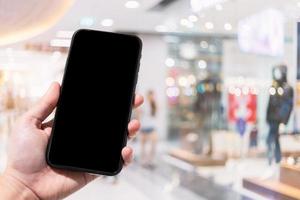 gros plan sur un smartphone à usage féminin, des images floues dans le centre commercial et un magasin de vêtements flou de l'arrière-plan. photo