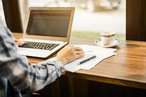 gros plan d'un homme d'affaires travaillant avec un ordinateur portable dans un café comme l'arrière-plan. photo