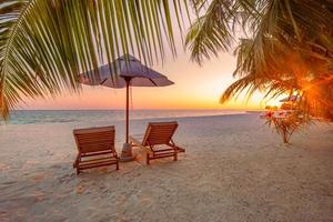 beau paysage tropical de coucher de soleil, deux chaises longues, chaises longues, parasol sous palmier. sable blanc, vue mer avec horizon, ciel crépusculaire coloré, calme et détente. hôtel balnéaire inspirant