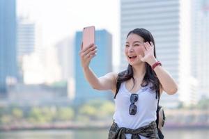 belle femme touristique asiatique utilise un appel vidéo via un smartphone dans le centre-ville urbain. voyage de vacances en été. photo