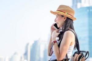 belle femme de tourisme solo asiatique souriante et aime parler via un téléphone portable dans le centre-ville. voyage de vacances en été. photo