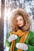 belle jeune fille dans une forêt d'hiver. portrait d'hiver de femmes vêtues de mitaines et d'écharpe photo