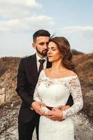 couple de mariage incroyable, la mariée et le marié se tenant la main sur un fond de montagnes et de rivière photo