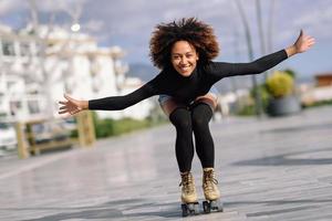 femme noire sur patins à roulettes équitation à l'extérieur sur la rue urbaine photo