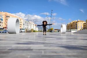 femme noire sur patins à roulettes équitation à l'extérieur sur la rue urbaine photo