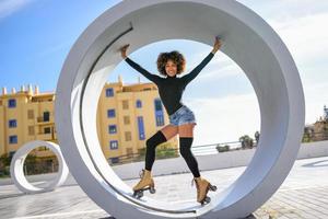 femme noire sur patins à roulettes équitation à l'extérieur sur la rue urbaine photo