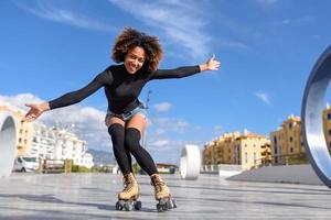 femme noire sur patins à roulettes équitation à l'extérieur sur la rue urbaine photo