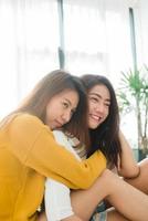 belles jeunes femmes asiatiques lgbt couple heureux lesbien assis sur le lit étreignant et souriant ensemble dans la chambre à la maison. couple de lesbiennes lgbt ensemble concept à l'intérieur. passer du bon temps à la maison. photo