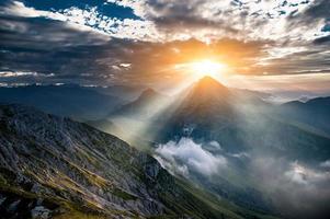 le soleil se lève derrière la montagne photo