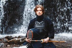 homme pratiquant le kendo avec une épée de bambou sur fond de cascade photo