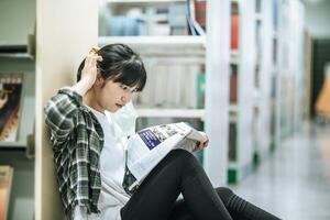 une femme assise lisant un livre dans la bibliothèque. photo