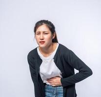 une femme debout avec un mal de ventre et appuie sa main sur son ventre. photo