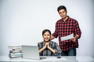 les hommes enseignent aux femmes comment travailler avec des ordinateurs portables au travail. photo