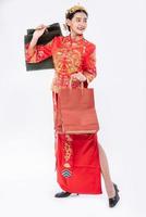 femme porter un costume cheongsam sourire avec un sac en papier du shopping dans le nouvel an chinois photo