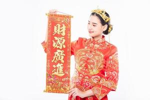 une femme porte un costume cheongsam heureux d'avoir reçu la carte de voeux chinoise du patron au nouvel an chinois