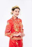 femme portant un costume cheongsam sourire pour accueillir les voyageurs faisant du shopping dans le nouvel an chinois photo