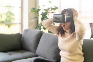femme latine à l'aide d'un casque de réalité virtuelle sur canapé photo