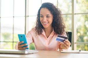 belle femme latine utilisant un smartphone avec carte de crédit photo
