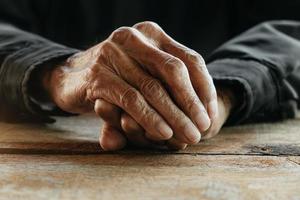 gros plan des mains ridées des hommes, le vieil homme porte sur la table en bois photo