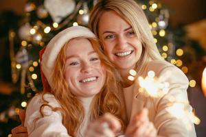 couple de lesbiennes en train de dîner pour célébrer des vacances. les filles brûlent des cierges magiques et sourient à la caméra photo