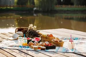 pique-niquer au parc près du lac. fruits frais, boissons pétillantes glacées et croissants par une chaude journée d'été. Déjeuner pique-nique. mise au point sélective photo