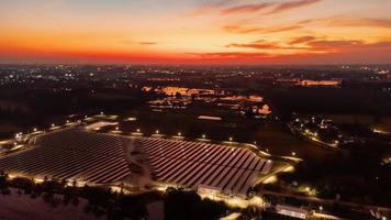 vue aérienne d'une ferme solaire produisant de l'énergie propre pendant la soirée au crépuscule. zone visible tout autour photo