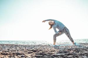 fille faisant du yoga et s'étirant sur la plage avec son chien photo