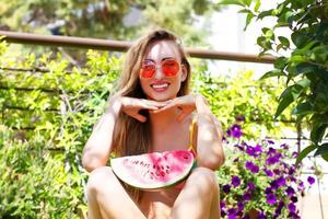 belle jeune femme avec pastèque dans un jardin tropical fleuri