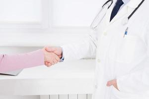 médecin et patient au bureau se serrant la main, concept de soins de santé et d'assistance. assurance médicale. doc assis dans le cabinet. homme en uniforme blanc. photo